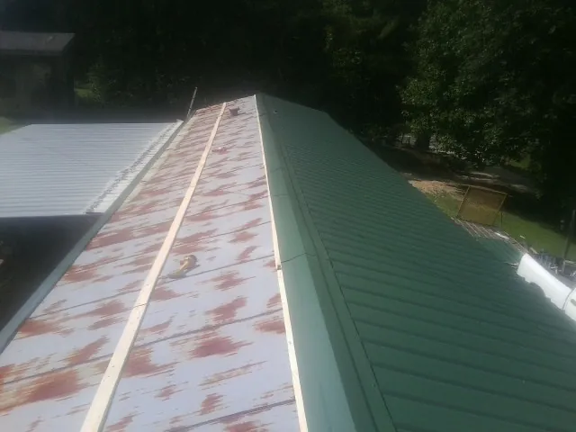 Old rusted panels beside newly installed green metal roofing — Wind Damage Roof Repair by Roofing Brothers in Phillipsburg