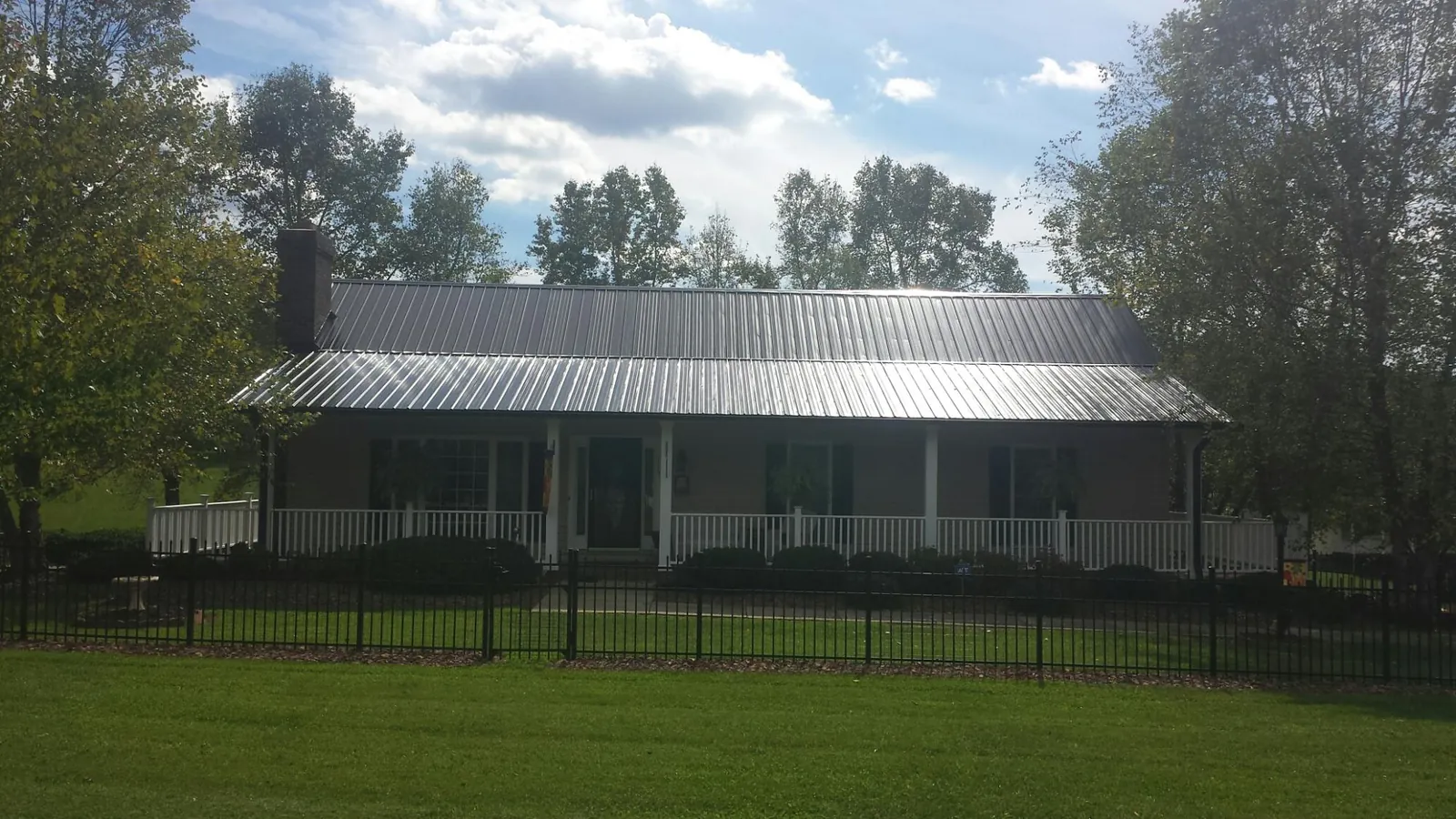 Gray metal roof on a brick ranch with a full width front porch — Gutter Guard Installation work by our crew in Phillipsburg